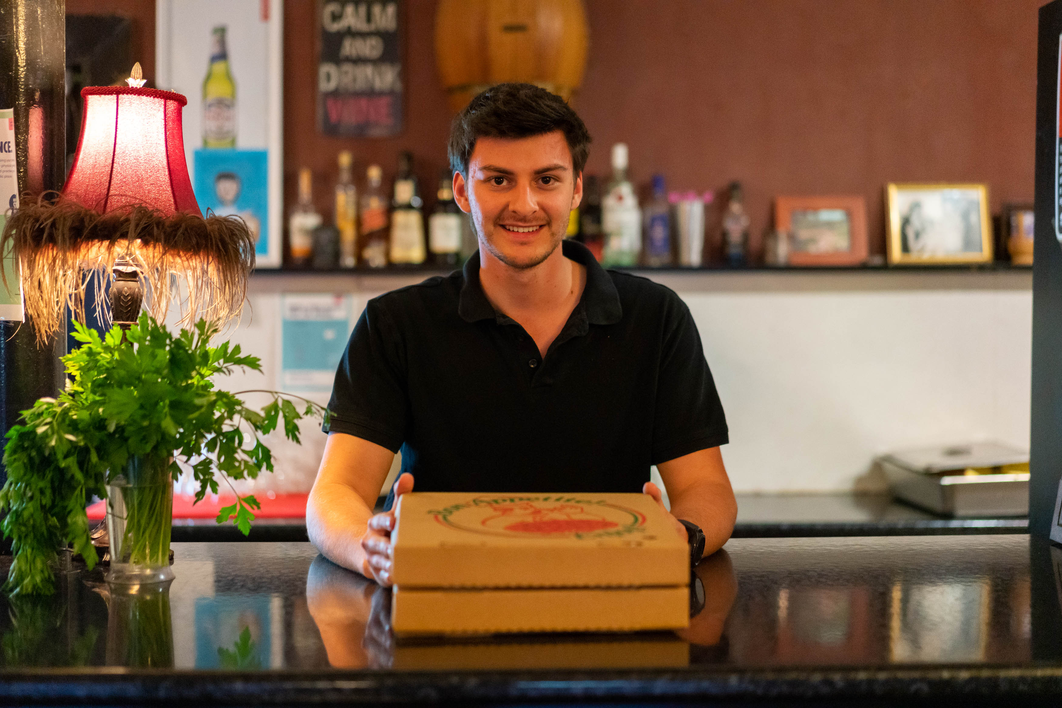 Man presenting pizza boxes at counter