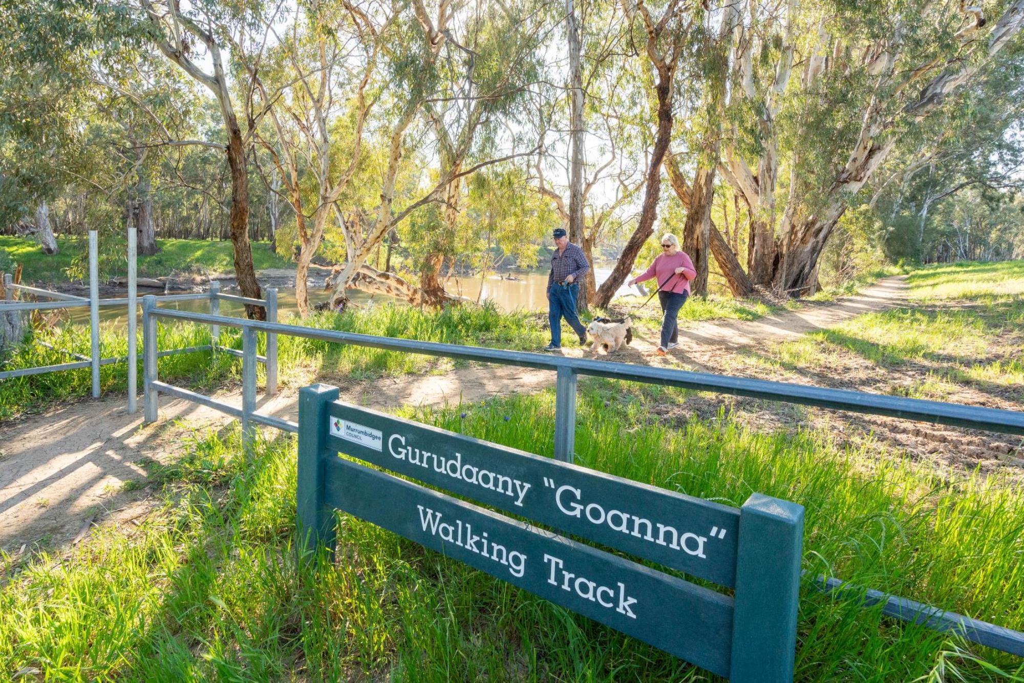 Couple walking dog along walking track